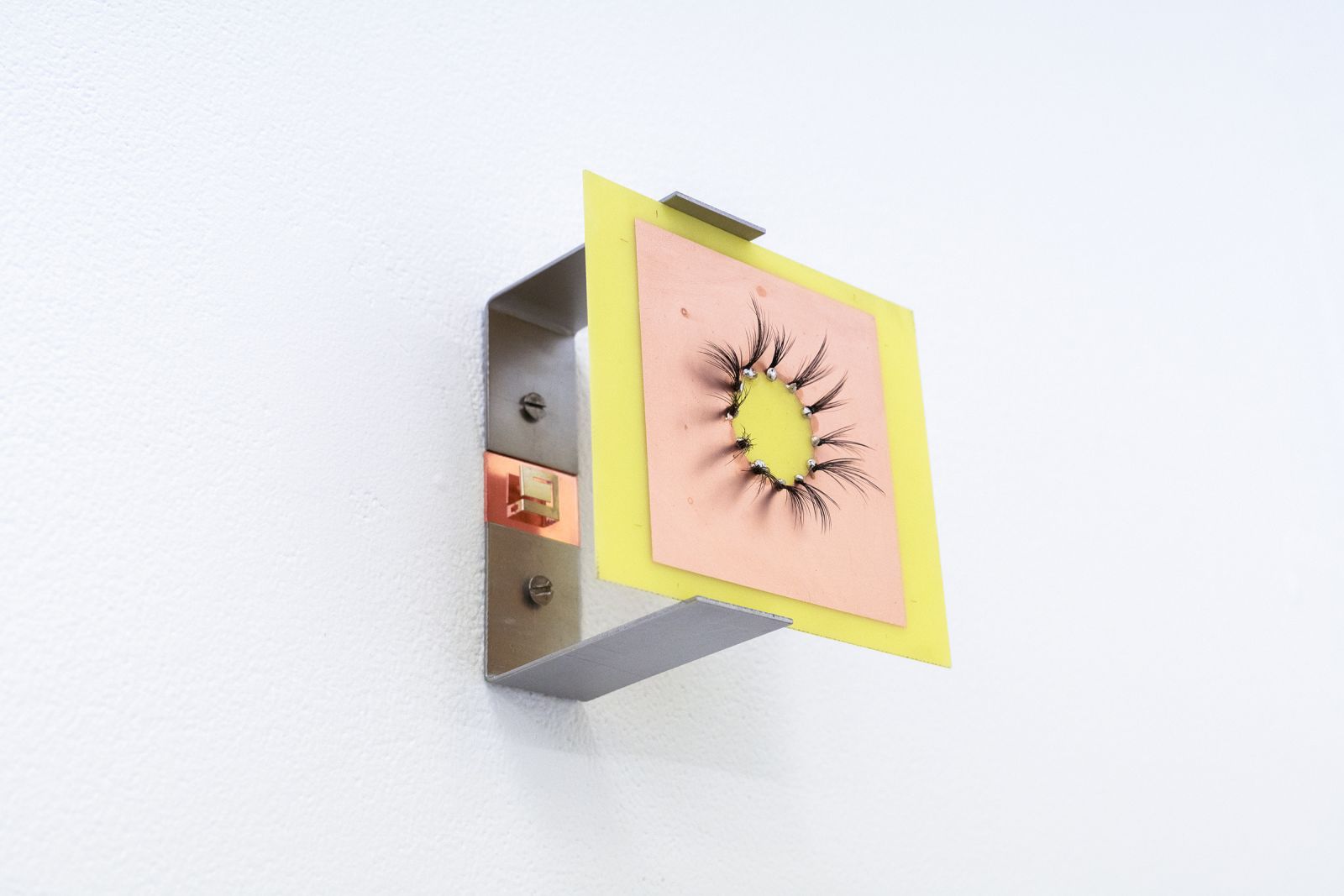 a small sculpture made out of metal and plastic hangs on the wall