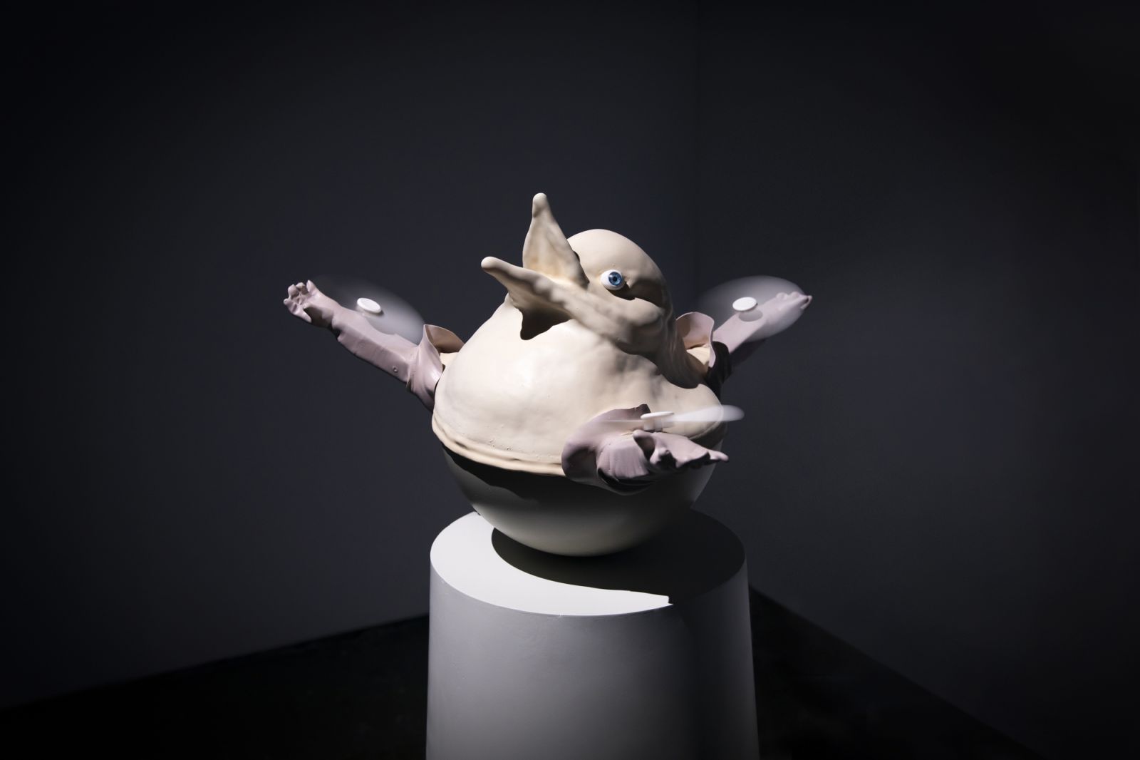 a toy-like bird sculpture with 3 hands and rotar blades
