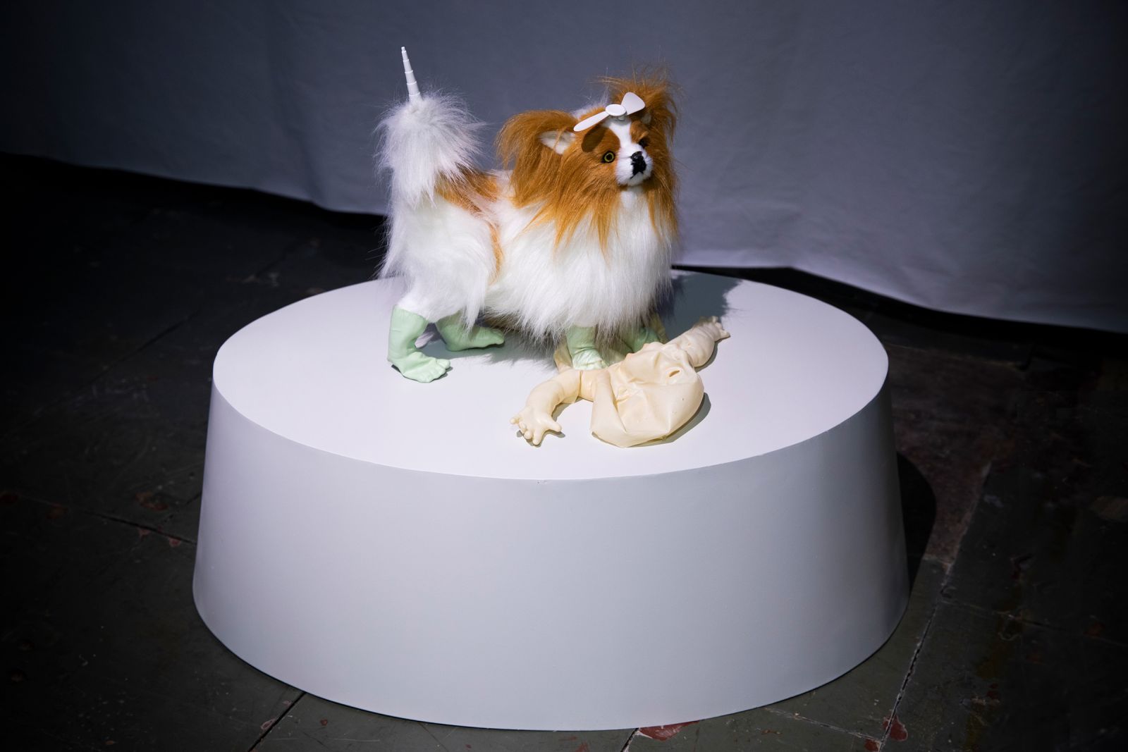 Sculpture with dog toy on a white oval-shaped pedestal