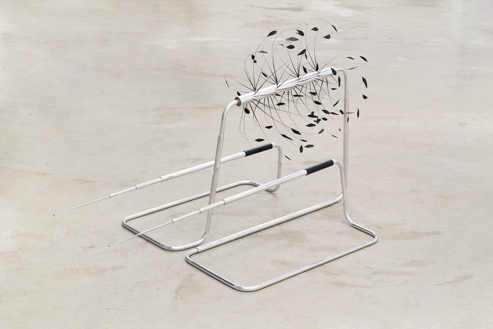 a metal sculpture made out of tube parts and black feathers